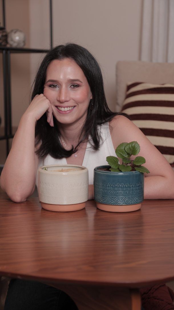Gisell sonriendo en una mesa con una planta