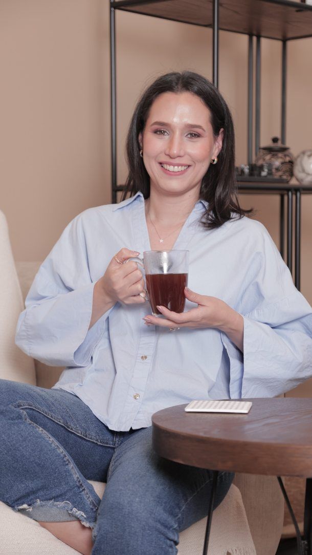 Gisell con una taza de té, sonriendo